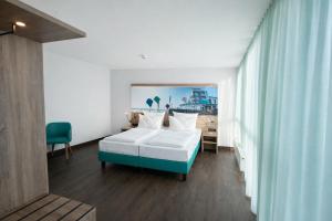 a bedroom with a bed and a table and a chair at Hotel Rheinpark Rees in Rees