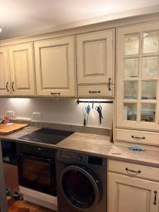 a kitchen with white cabinets and a washing machine at Kilpedder cottage in Kilpedder