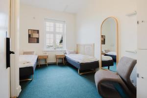 a hospital room with three beds and a mirror at Nomad City Hotel - Odense in Odense