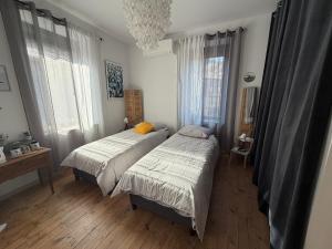 a bedroom with two beds and a chandelier at L'Etape des Jacquets - Monistrol d'allier in Monistrol-dʼAllier