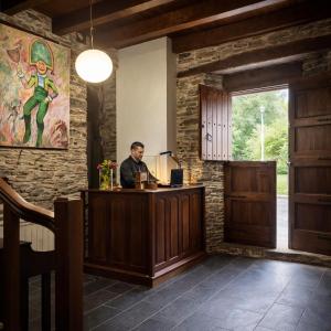a man sitting at a reception desk in a room with a painting at Casa do Fidalgo in A Pontenova