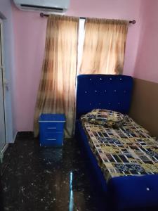 a bedroom with a blue bed and a window at Aduniniyi 7 Shines in Igando