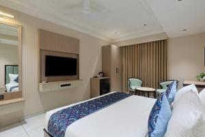 a hotel room with a bed and a flat screen tv at Hotel Ramida Suites IGI Delhi Airport in New Delhi