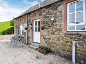 a stone cottage with a table and chairs outside at 1 Bed in Biggar oc-82923 in Biggar