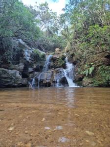 a waterfall in the middle of a river at Chalé do Ben in São Thomé das Letras