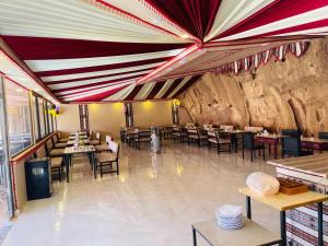 a restaurant with tables and chairs and a stone wall at Wadi rum lacshre in Disah