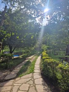 a stone path in a park with the sun shining at Chalé do Ben in São Thomé das Letras
