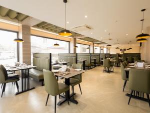 a dining room with tables and chairs and windows at Hotel Rio in Siliguri