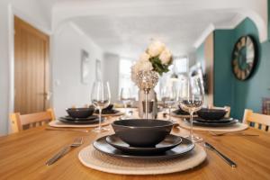 a wooden table with plates and wine glasses on it at Delves House in Bescot
