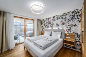 a bedroom with a white bed with a floral wallpaper at Schmuckstück Ferienapartments Bodenmais inkl aktivCARD in Bodenmais