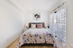 a white bedroom with a large bed with pink pillows at Central Condo-Pool with AC and garden by Algarve Dream Holidays in Albufeira