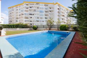 a swimming pool in front of a tall apartment building at Central Condo-Pool with AC and garden by Algarve Dream Holidays in Albufeira
