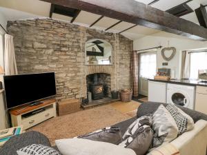 a living room with a couch and a stone fireplace at In & Out Cottage in Leyburn
