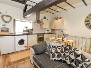 a living room with a couch and a kitchen at In & Out Cottage in Leyburn