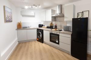 a kitchen with white cabinets and a black refrigerator at Spacious City Centre Apartment with Balcony in Wolverhampton