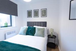 a bedroom with a white bed with blue pillows at Spacious City Centre Apartment with Balcony in Wolverhampton