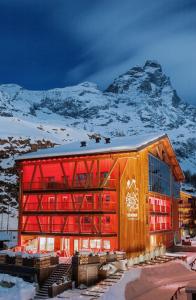 a large wooden building with a mountain in the background at Aux Pieds du Roi - Suite & Spa in Breuil-Cervinia