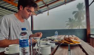 a man sitting at a table with a plate of food at Rainforest Jungle Chill Singharaja in Deniyaya