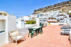 a patio with tables and chairs on a balcony with white buildings at Casa Arno - Lovely Renovated Apartment In Playa De Mogan in Puerto de Mogán