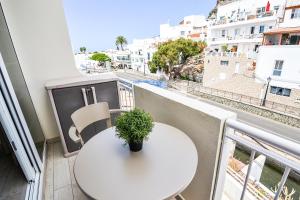 a white table and a plant on a balcony at Casa Arno - Lovely Renovated Apartment In Playa De Mogan in Puerto de Mogán