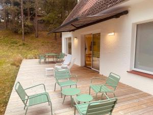 a deck with green chairs and tables on a house at Villa la Hune- Proche Golfs & Plage in Neufchâtel-Hardelot