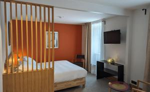 a hotel room with a bed and a television at Logis Hôtel et Restaurant La Pension du Moulin in Pont-Aven