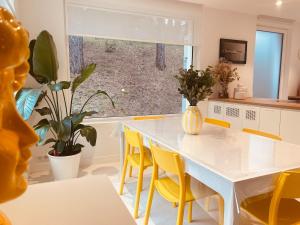 a kitchen with a white table and yellow chairs at Villa la Hune- Proche Golfs & Plage in Neufchâtel-Hardelot