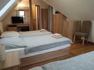 a bedroom with two beds and a desk and a chair at The Corner House Panzió in Tata