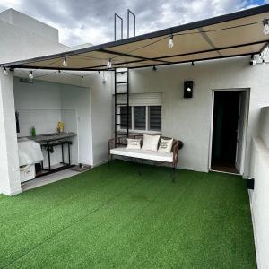 a patio with a green floor and a couch at Pepe Hostel Boutique in Neuquén