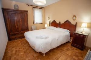 a bedroom with a large white bed with a wooden headboard at Casa Celia by CARDI SUITES in Panticosa