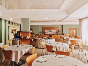 a dining room with tables and chairs and a kitchen at Hotel Planet International in Arezzo