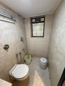 a bathroom with a toilet and a window at Hotel Sweet Inn in Mumbai