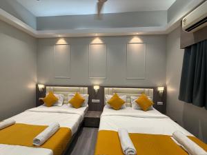 two beds in a room with yellow pillows at Hotel Sweet Inn in Mumbai
