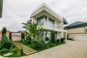a large white house with a palm tree in front of it at Lanai Villas Beach Side in Baku