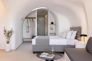 a bedroom with a bed and a living room at Filomare Oia Suites in Oia +69 photos