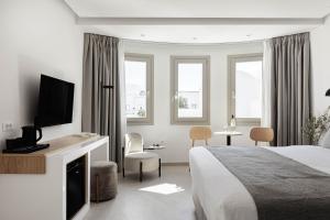 a hotel room with a bed and a tv at Filomare Oia Suites in Oia