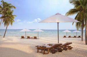 a beach with chairs and umbrellas and the ocean at KHEM BEACH Hotel in Phú Quốc