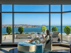 a woman sitting in a chair in front of a window at Swissotel The Bosphorus Istanbul in Istanbul