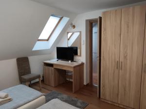 a bedroom with a desk with a computer and a window at The Corner House Panzió in Tata