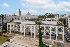 ein weißes Gebäude mit einer Palme davor in der Unterkunft Hotel Le Musée in Rabat