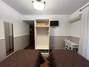 a room with two beds and a desk and a television at Hostal Hueso in Trujillo