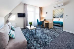 a hotel room with a couch and a bed and a desk at Hotel Eureka in Sopot