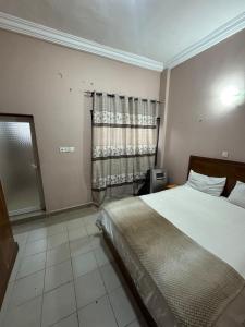 a bedroom with a large bed and a window at Jassehs Apartments in Brusubi