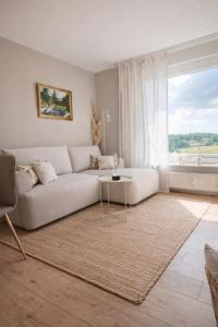 a living room with a white couch and a table at Strandhafer-Balkon mit Meerblick- 2 Min zum Strand in Schausende