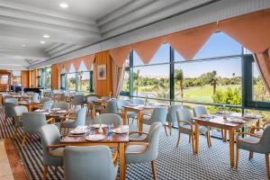 a restaurant with tables and chairs and large windows at Hilton Pyramids Golf in 6th Of October