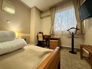 a bedroom with a bed and a desk and a window at Garni Hotel Lav in Belgrade