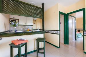 a kitchen with two green stools and a counter at BLUESEA Puerto Caleta in Caleta De Fuste