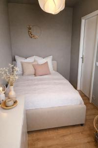 a bedroom with a white bed with pink pillows at Strandhafer-Balkon mit Meerblick- 2 Min zum Strand in Schausende