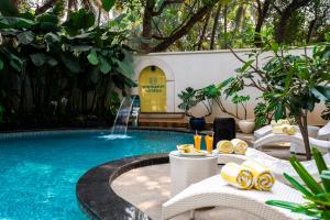 a swimming pool with a table and a fountain at Staymaster Veridian Standard 2BHK Near Calangute Beach in Calangute