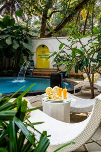 a table with drinks on it next to a swimming pool at Staymaster Veridian Standard 2BHK Near Calangute Beach in Calangute